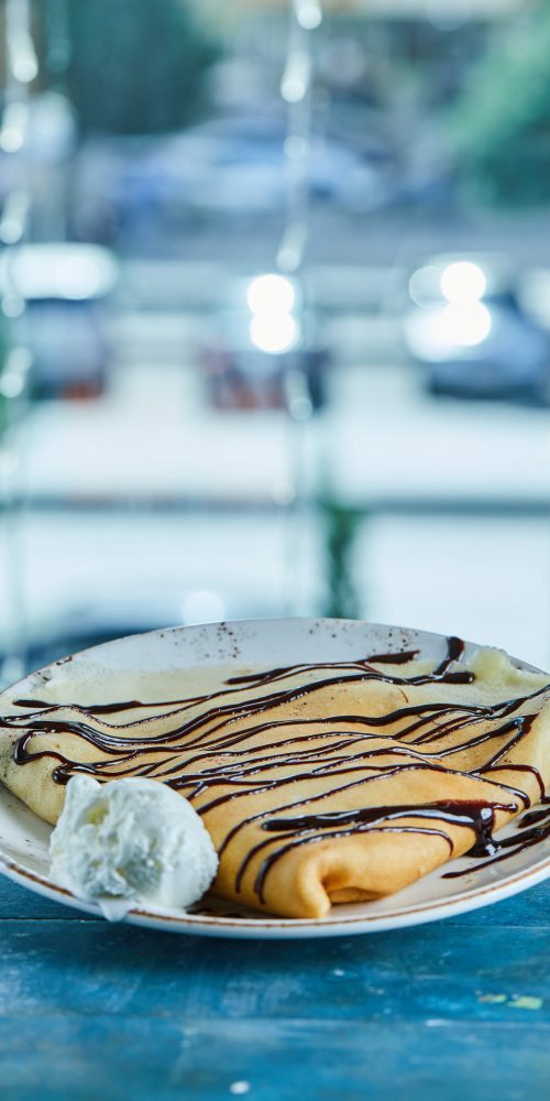 pancakes with vanilla ice cream, chocolate on the white plate in the blue background